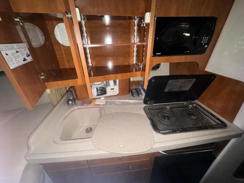 Slide: The Image of 2005 Four Winns 298 Vista boat kitchen with stove, sink, and microwave. - 14