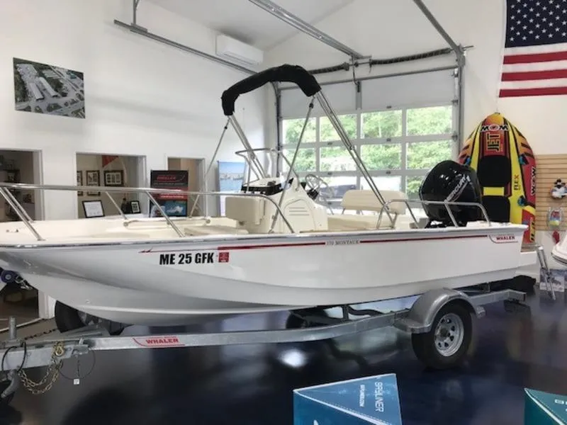 Slide: The Image of 2023 Boston Whaler 170 Montauk boat displayed indoors on a trailer. - 2