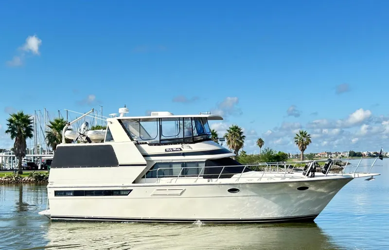 Slide: The Image of 1989 Carver Californian 48 yacht on calm water with palm trees in the background. - 11