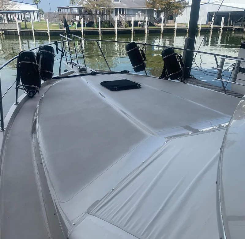 Slide: The Image of 1989 Carver Californian 48 yacht docked, showcasing spacious deck and sleek design. - 12