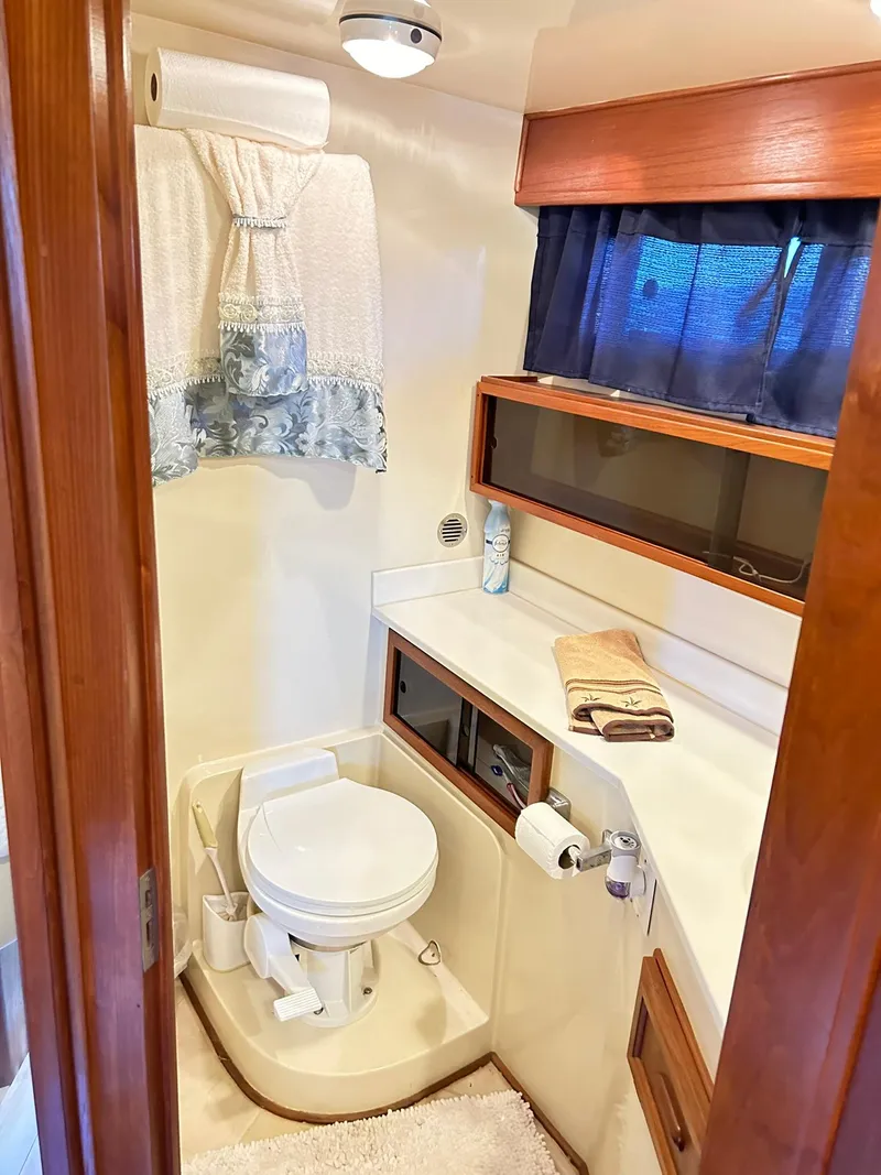 Slide: The Image of 1989 Carver Californian 48 yacht bathroom with toilet, sink, and wooden cabinetry. - 44