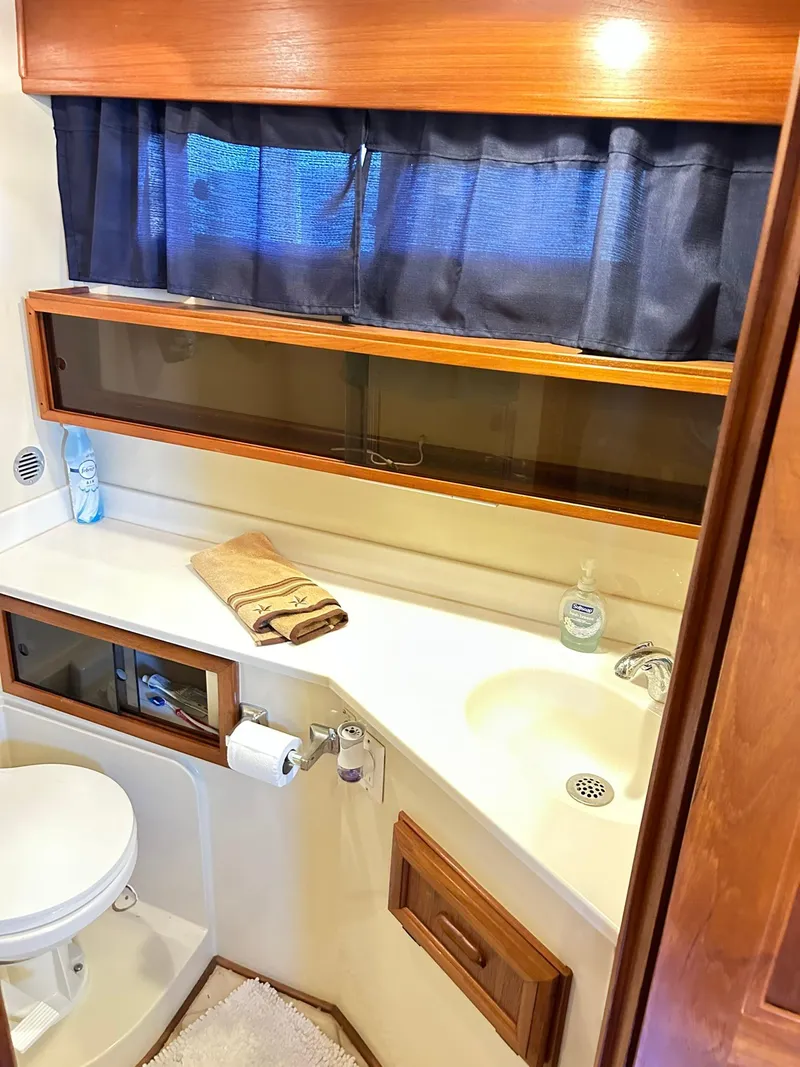 Slide: The Image of 1989 Carver Californian 48 yacht bathroom with sink, toilet, and wooden cabinetry. - 48
