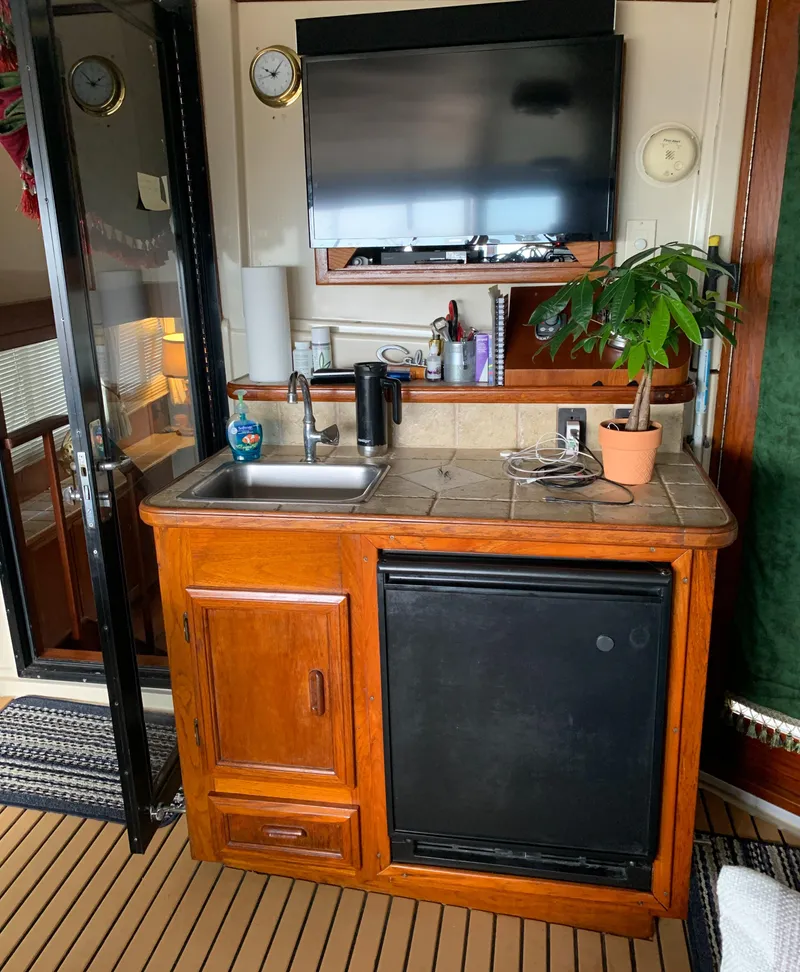 Slide: The Image of 1989 Carver Californian 48 yacht interior with kitchenette, sink, fridge, and potted plant. - 24