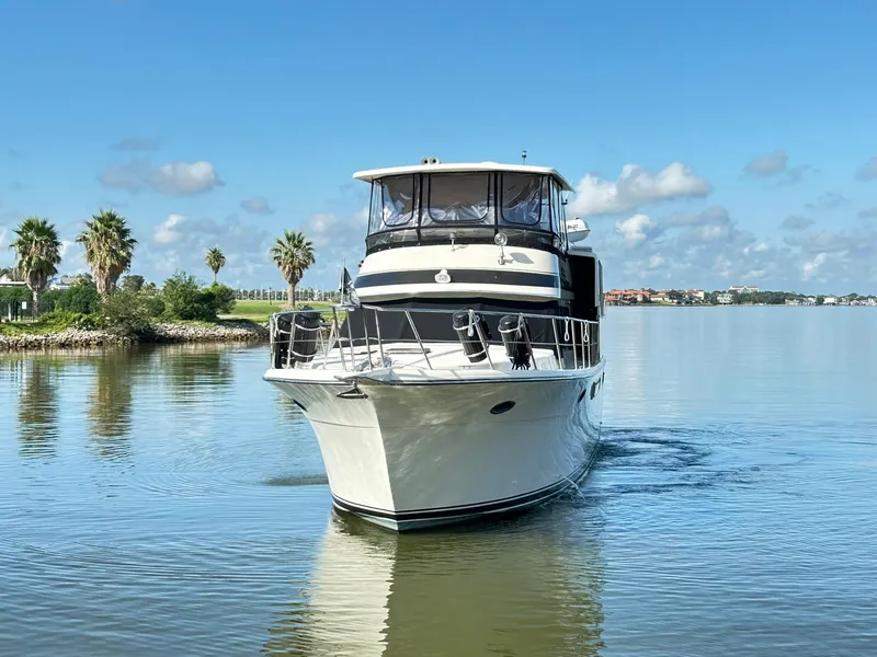 Slide: The Image of 1989 Carver Californian 48 yacht cruising on a calm lake under a clear blue sky. - 5