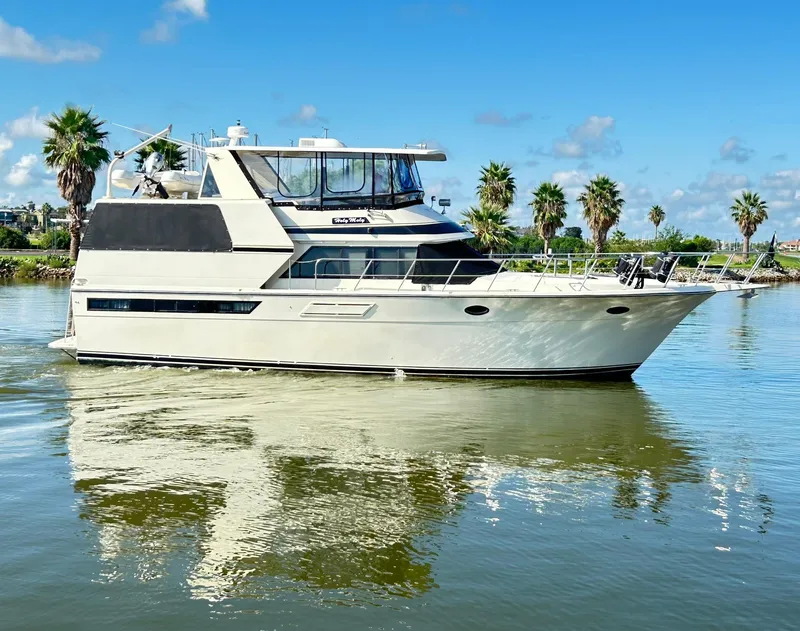 Slide: The Image of 1989 Carver Californian 48 yacht on calm water with palm trees in the background. - 8