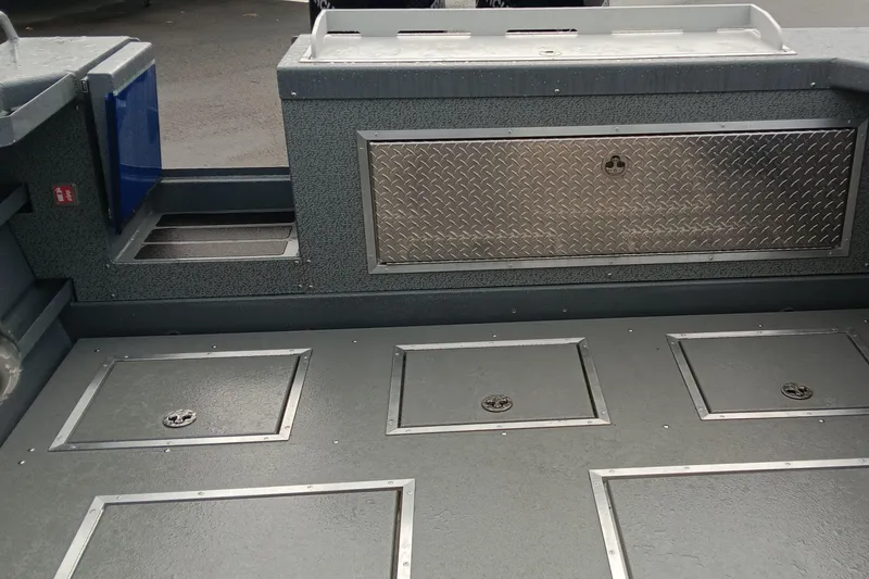 Slide: The Image of 2025 Spartan 2800 Olympia boat interior with storage compartments and diamond plate panel. - 12