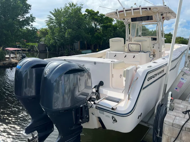 Slide: The Image of 2011 Grady-White Canyon 306 boat with dual outboard motors docked by lush greenery. - 3