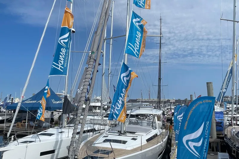 Slide: The Image of 2023 Hanse 460 yacht docked with branded flags under a clear sky. - 19