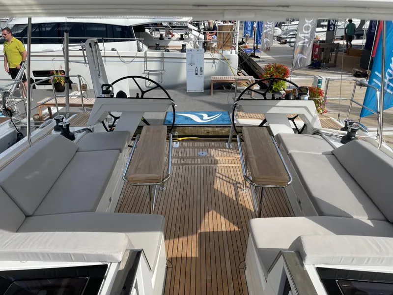Slide: The Image of 2023 Hanse 460 yacht deck with dual steering wheels and seating area. - 6