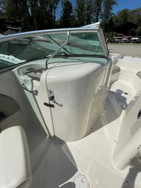 Slide: The Image of 2002 Sea Ray 220 Bow Rider interior with seating and windshield, docked outdoors. - 10