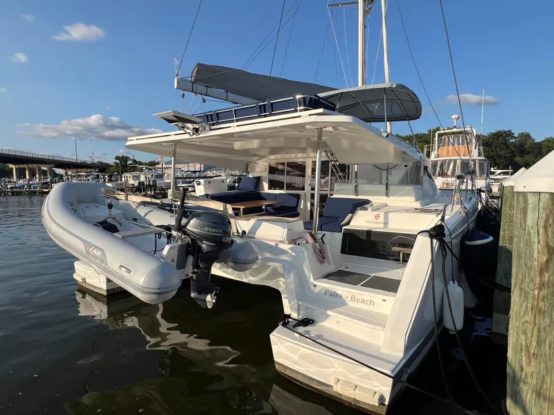 Slide: The Image of 2020 Fountaine Pajot Elba 45 catamaran docked, featuring a dinghy and spacious deck. - 4