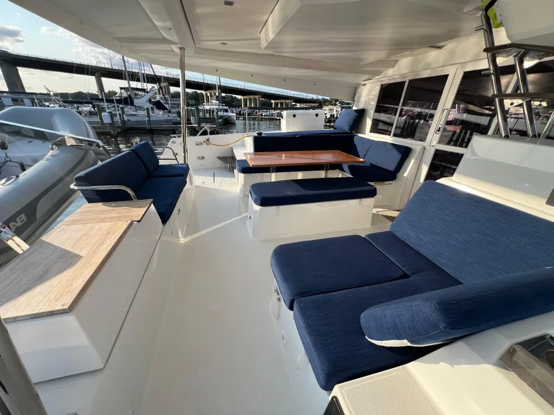 Slide: The Image of Spacious deck of 2020 Fountaine Pajot Elba 45 catamaran with blue seating and wooden tables. - 6