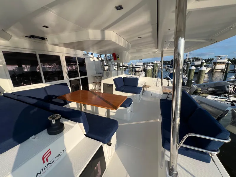 Slide: The Image of Spacious deck of 2020 Fountaine Pajot Elba 45 catamaran with blue seating and wooden table. - 8