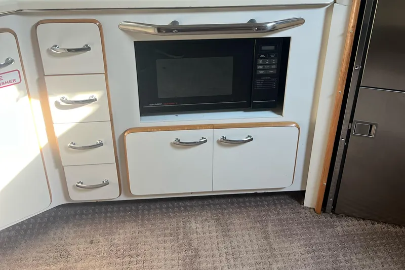 Slide: The Image of Kitchen area of 1990 Sea Ray 420 Sundancer with microwave and storage cabinets. - 11
