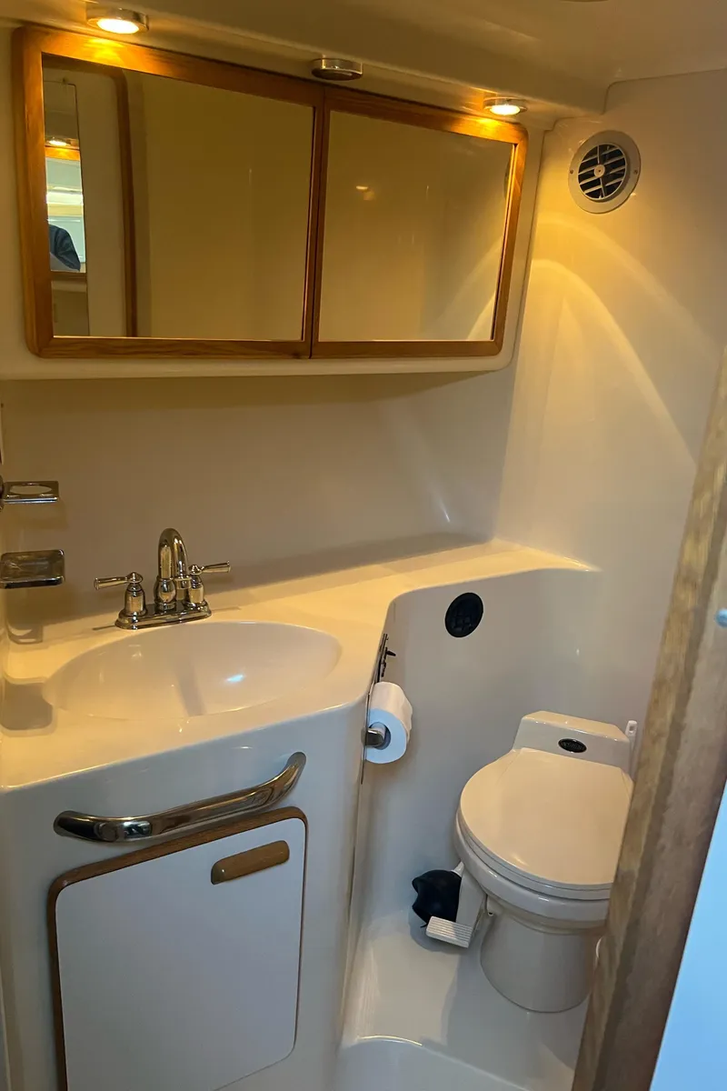 Slide: The Image of 1990 Sea Ray 420 Sundancer bathroom with sink, toilet, and mirrored cabinet. - 12