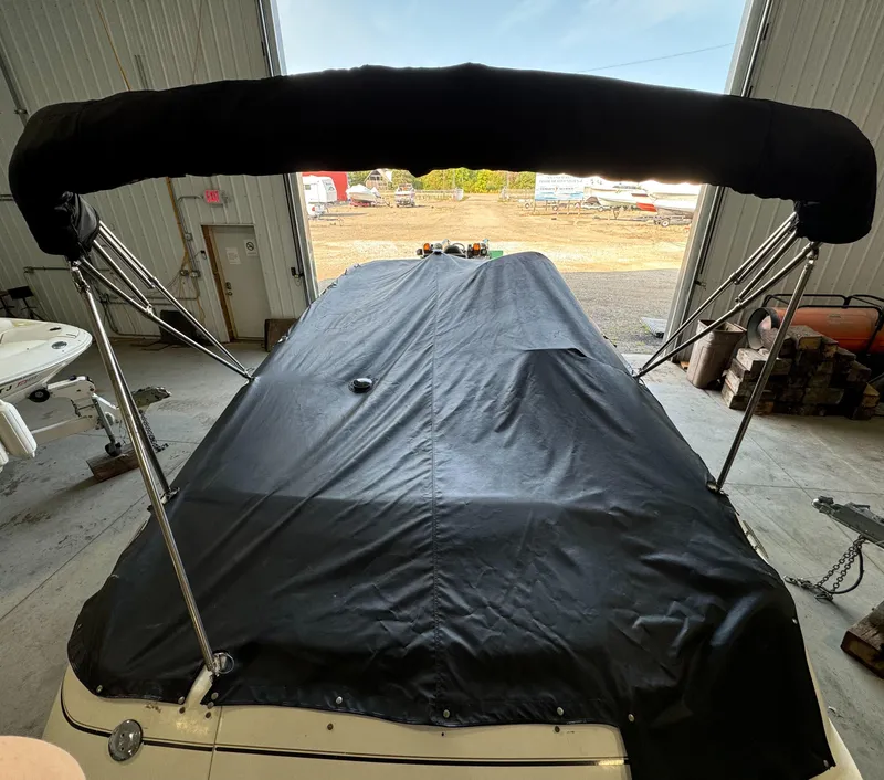 Slide: The Image of 2004 Glastron DX 215 boat with black cover in storage facility. - 9