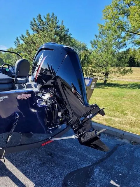 Slide: The Image of 2025 Tracker Pro Guide V-16 WT boat with Mercury outboard motor in a sunny park setting. - 2