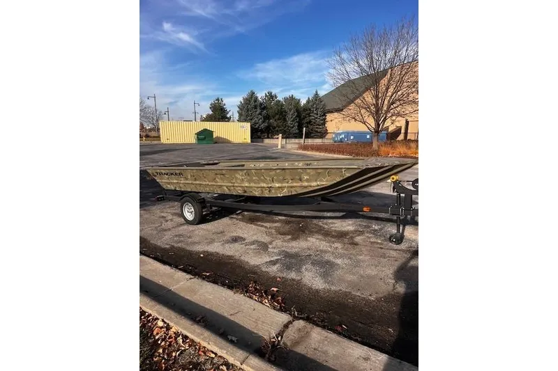 Slide: The Image of 2025 Tracker Grizzly 1648 Jon boat on trailer in parking lot, clear sky background. - 20