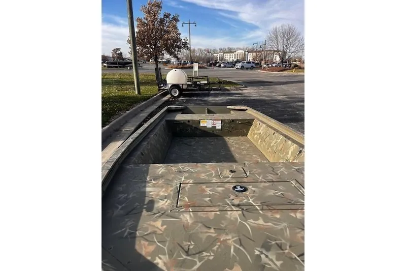 Slide: The Image of 2025 Tracker Grizzly 1648 Jon boat with camouflage design in a parking lot. - 21
