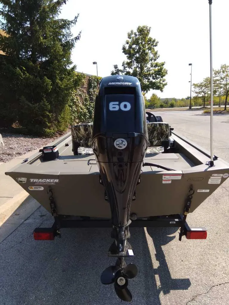 Slide: The Image of 2025 Tracker Grizzly 1754 SC boat with Mercury 60 outboard motor, parked outdoors. - 4