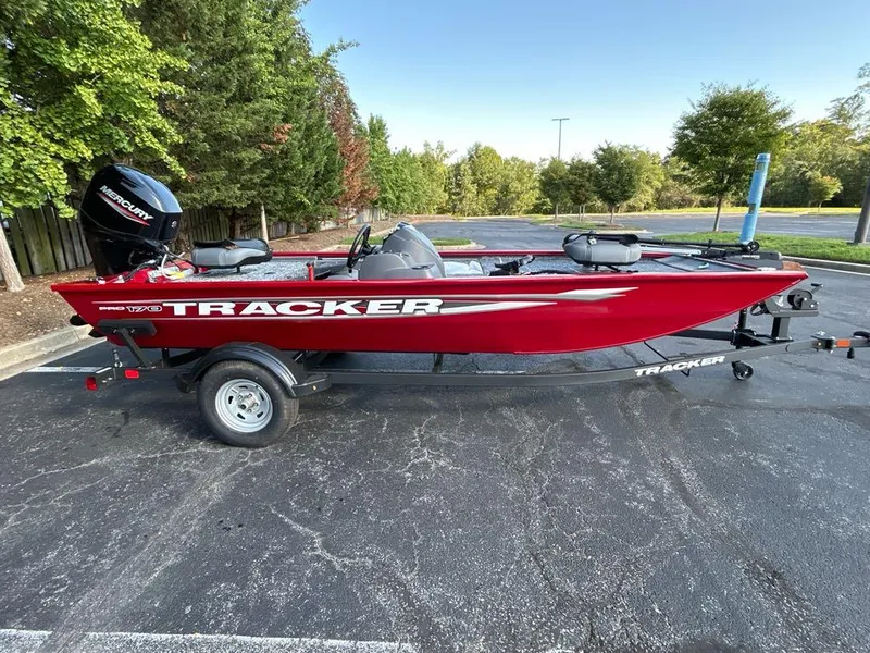 Slide: The Image of 2025 Tracker Pro 170 boat in red, parked on a trailer in a scenic outdoor setting. - 2