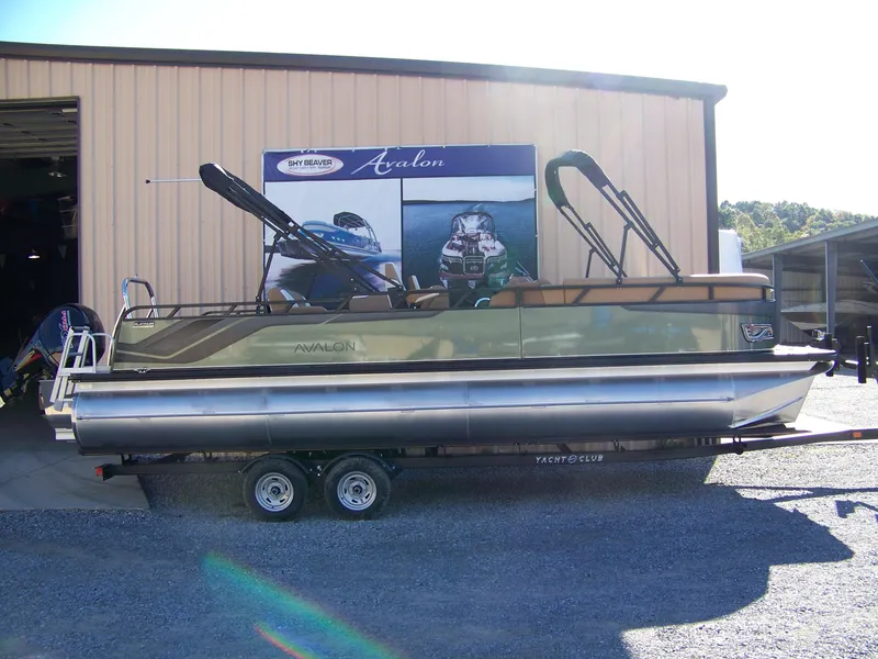 The Image of 2025 Avalon Ven25VRB pontoon boat on trailer outside a warehouse. - 1