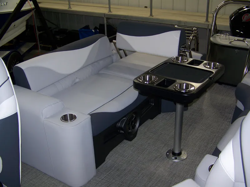 Slide: The Image of 2025 Avalon LSZ23QLS boat interior with plush seating and a table featuring cup holders. - 14