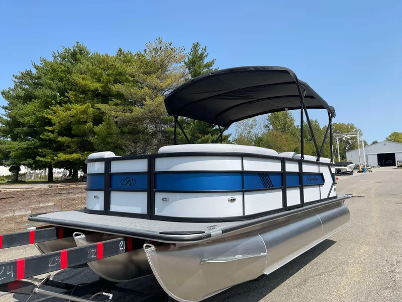 Slide: The Image of 2025 Bentley Pontoons Bolt 223 on trailer, featuring sleek design and canopy, parked outdoors. - 0