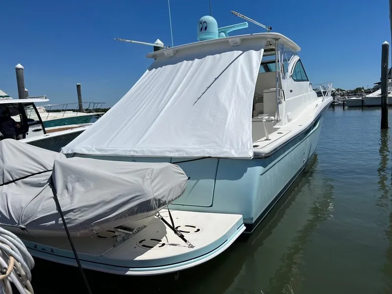 Slide: The Image of 2005 Tiara Yachts 4200 Open docked, featuring a covered rear deck and clear blue sky. - 4