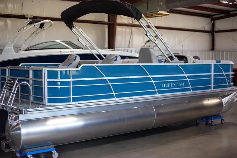 The Image of 2025 Trifecta 24TRFC LE pontoon boat in a showroom, featuring a sleek blue design. - 1