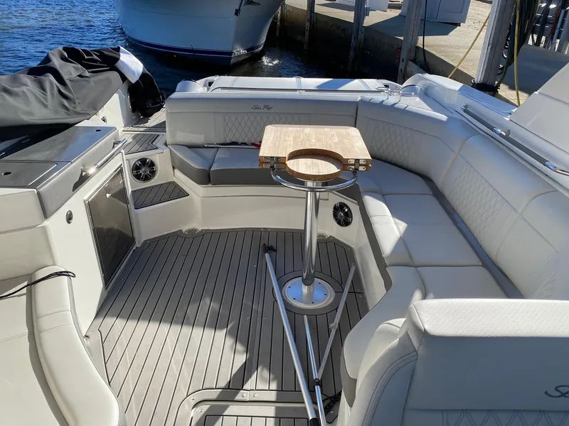 Slide: The Image of 2020 Sea Ray SLX 350 boat interior with seating and table, docked by the water. - 16