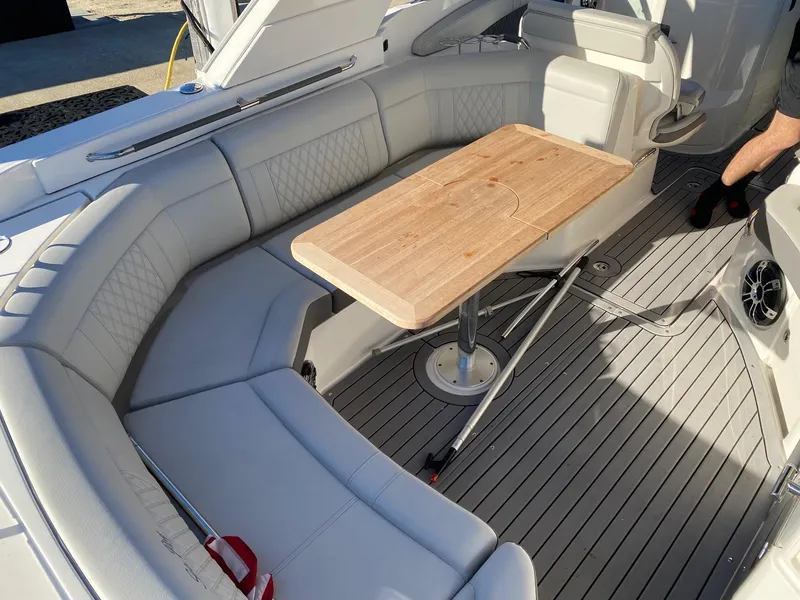 Slide: The Image of 2020 Sea Ray SLX 350 boat interior with cushioned seating and wooden table. - 19