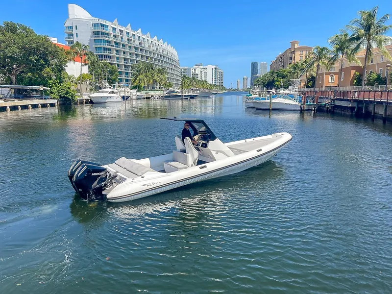 Slide: The Image of 2025 Ribco Venom 30 boat cruising in a scenic urban waterway. - 6