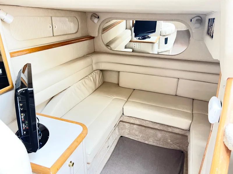 Slide: The Image of 1997 Sea Ray 330 Sundancer Cruiser interior with beige seating and TV. - 11