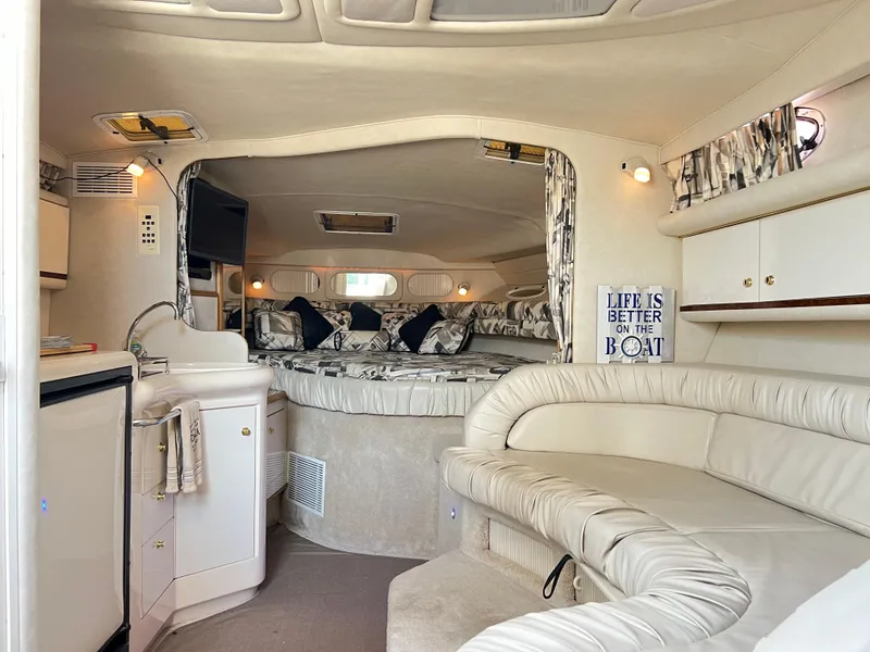 Slide: The Image of 1997 Sea Ray 330 Sundancer Cruiser interior with cozy seating, kitchenette, and sleeping area. - 13