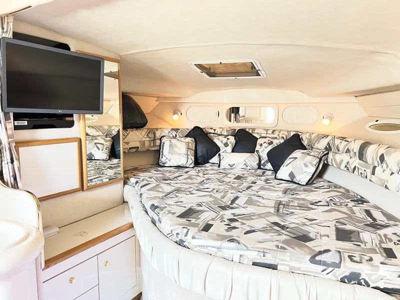 Slide: The Image of 1997 Sea Ray 330 Sundancer Cruiser interior with patterned bedding and mounted TV. - 14