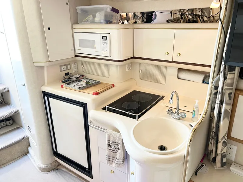 Slide: The Image of 1997 Sea Ray 330 Sundancer Cruiser kitchen with sink, stove, microwave, and storage cabinets. - 17
