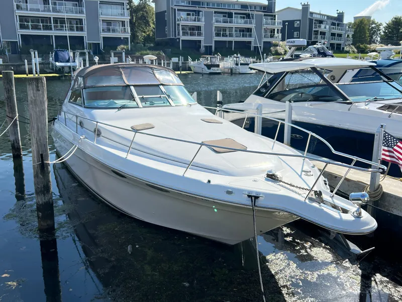 Slide: The Image of 1997 Sea Ray 330 Sundancer Cruiser docked at marina with modern buildings in background. - 2