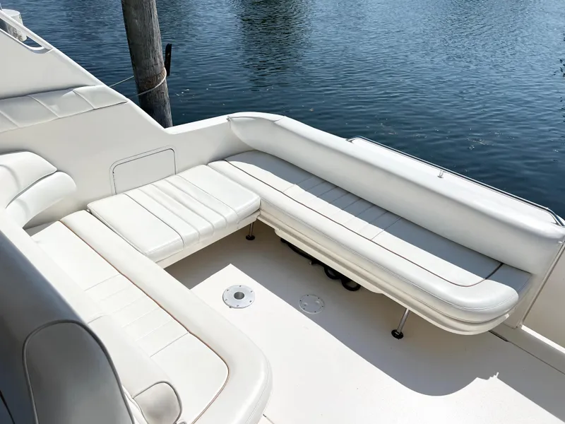 Slide: The Image of 1997 Sea Ray 330 Sundancer Cruiser with white seating by the water. - 7