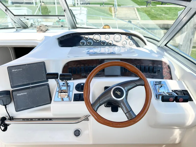 Slide: The Image of 1997 Sea Ray 330 Sundancer Cruiser helm with wooden steering wheel and navigation controls. - 9
