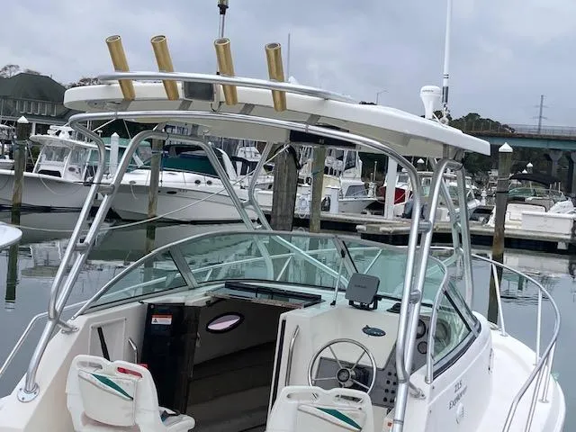 Slide: The Image of 2004 Aquasport 215 Explorer boat docked in marina, featuring a sleek design and fishing rod holders. - 10