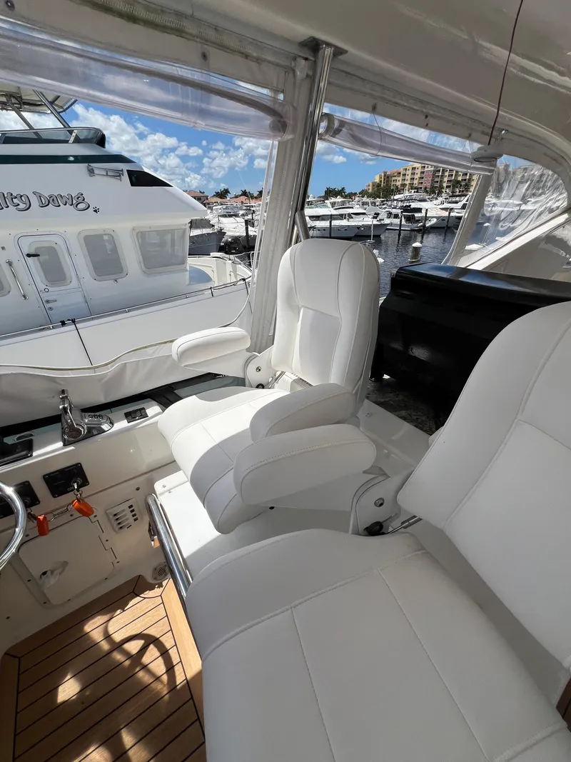 Slide: The Image of Luxurious 2005 Neptunus 62 Flybridge yacht interior with white seating and marina view. - 16