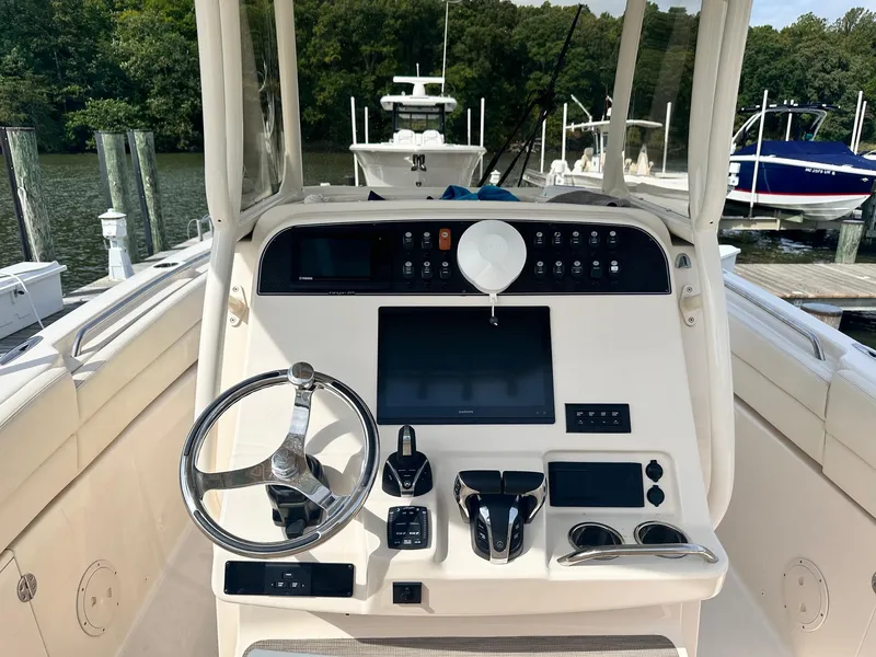 Slide: The Image of 2022 Grady-White Canyon 271 boat dashboard with steering wheel and navigation controls. - 12