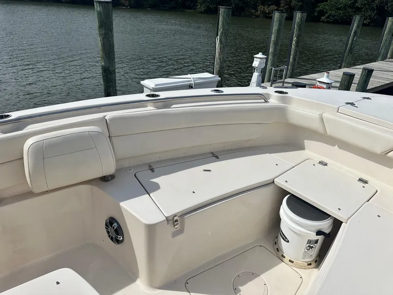 Slide: The Image of 2022 Grady-White Canyon 271 boat interior with seating and storage, docked by the water. - 17