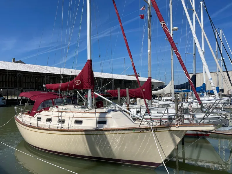The Image of 1992 Island Packet 32 sailboat docked in marina with red sails. - 1