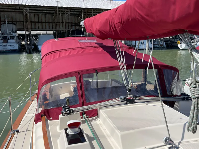 Slide: The Image of 1992 Island Packet 32 sailboat with red canopy docked at marina. - 10