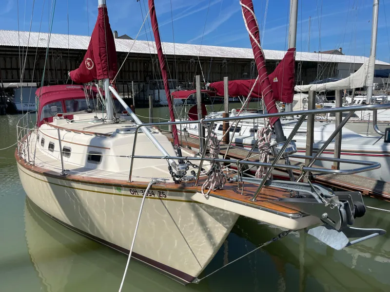 Slide: The Image of 1992 Island Packet 32 sailboat docked with red sails and white hull. - 2