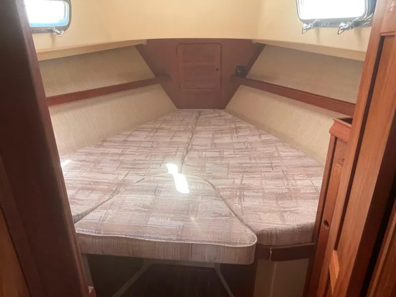 Slide: The Image of 1992 Island Packet 32 sailboat interior with V-berth and beige cushions. - 28