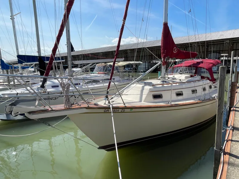 Slide: The Image of 1992 Island Packet 32 sailboat docked in marina, featuring red sails and white hull. - 3