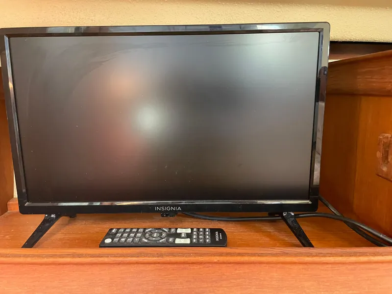 Slide: The Image of Insignia TV with remote on wooden shelf in 1992 Island Packet 32 yacht. - 31